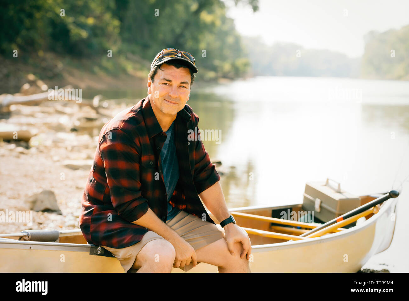Portrait of mid adult man sitting on boat at lakeshore Stock Photo