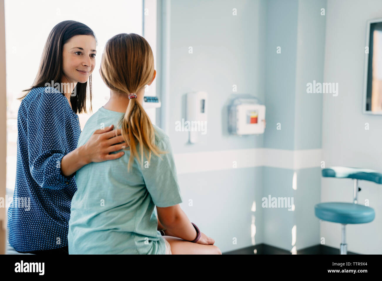 Mother and daughter sitting in medical examination room at hospital Stock Photo