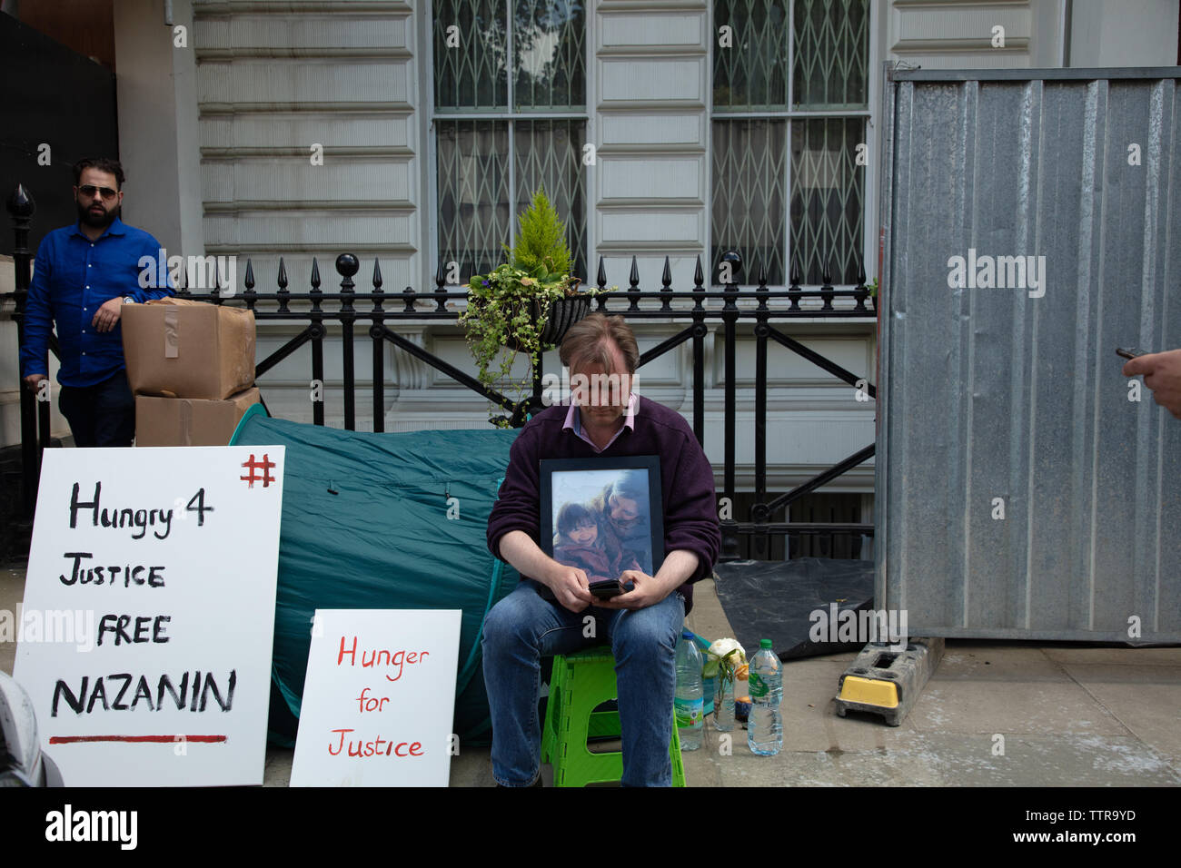 London, UK. 17th June 2019. Richard Ratcliffe on hunger strike in front of the Iranian embassy in London in protest of the detention of his wife Nazanin Zaghari in Iran over spying allegations. Embassy staff and builders bring more material on the paving, reducing Richards space. Credit: Joe Kuis / Alamy Stock Photo