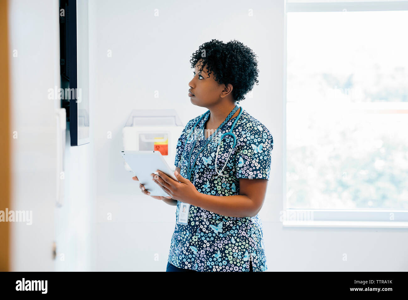 Female doctor looking at flat screen while holding tablet computer in hospital Stock Photo