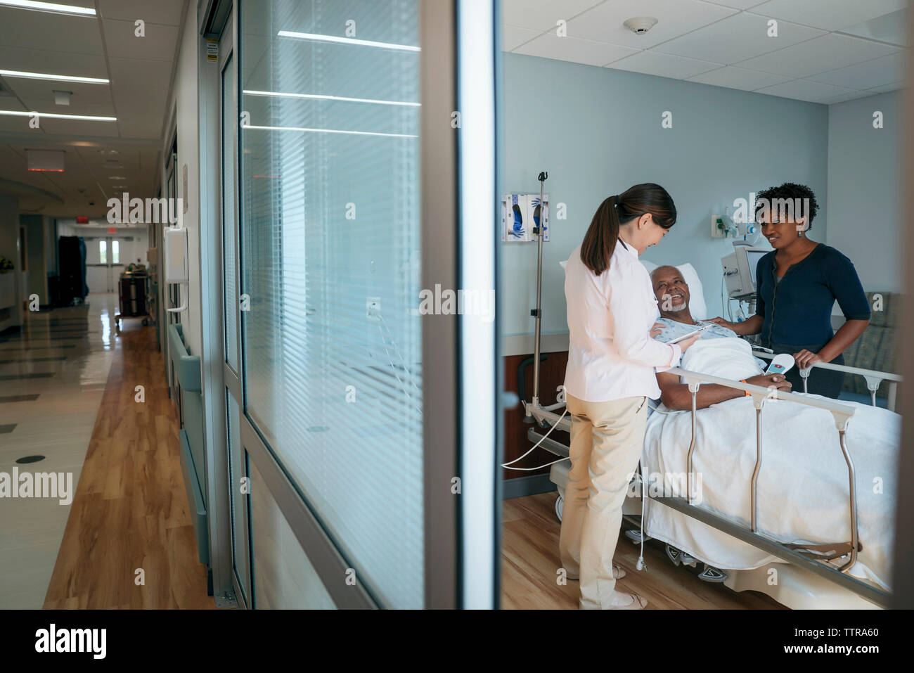 Female doctor talking with senior patient and woman in hospital ward ...