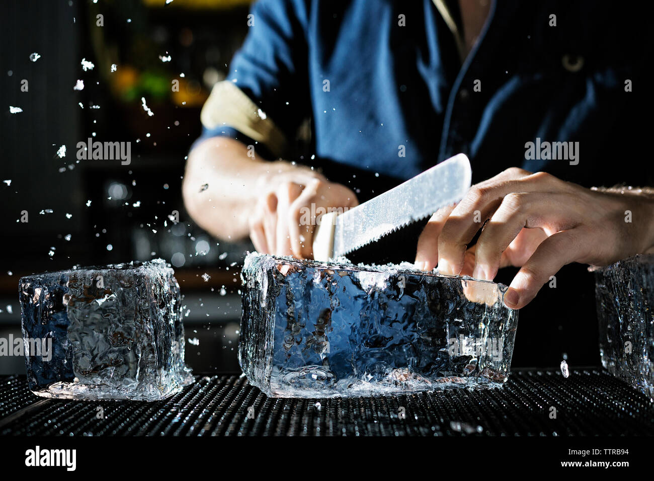 Midsection of chef breaking ice block in kitchen Stock Photo