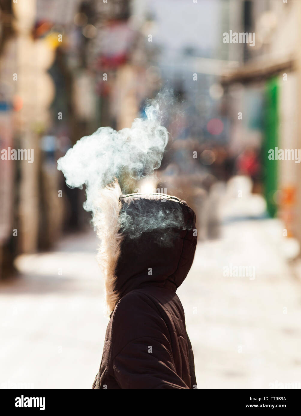 Digital composite image of smoke coming out from woman's hood Stock Photo