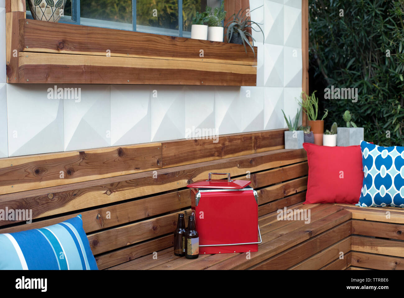Beer bottles and cooler on wooden bench in backyard Stock Photo