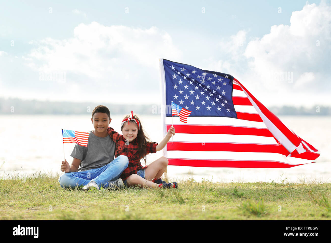 Boy and girl holding American flag on river bank Stock Photo - Alamy