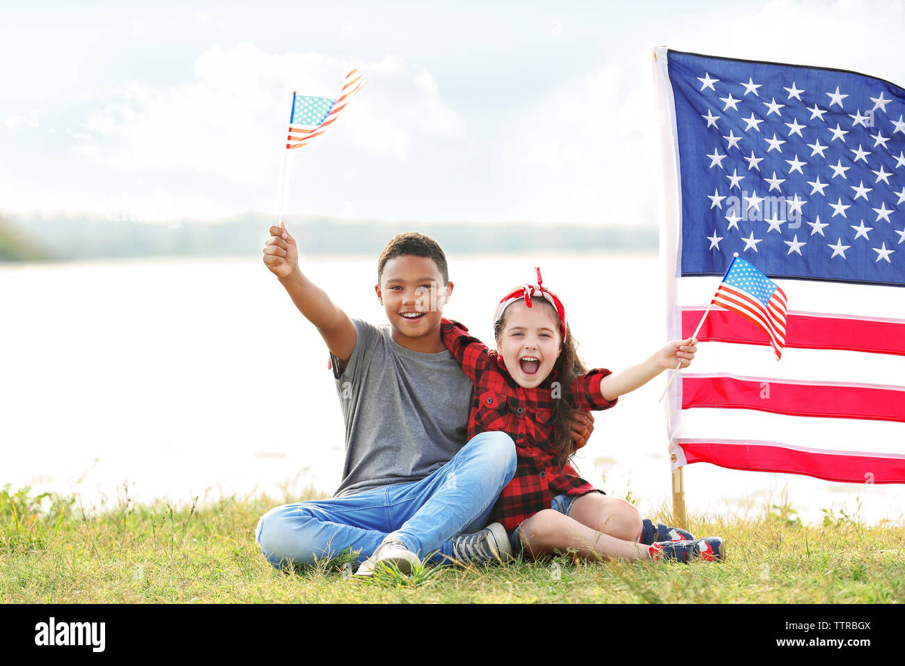 Boy and girl holding American flag on river bank Stock Photo - Alamy