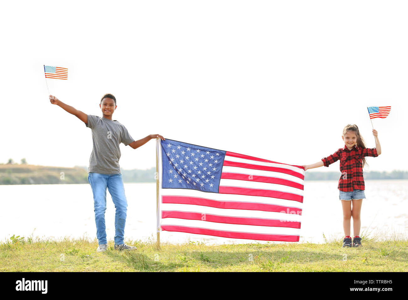 Boy and girl holding American flag on river bank Stock Photo - Alamy