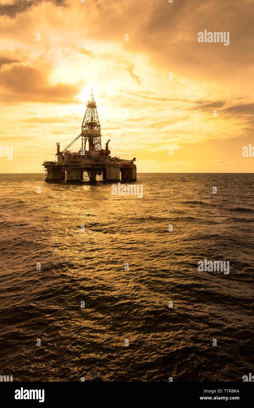 Oil platform in sea against cloudy sky Stock Photo