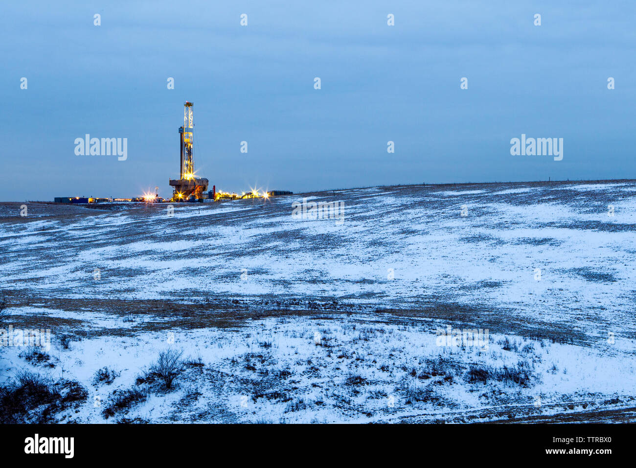 View of oil rig on snow covered land against sky Stock Photo