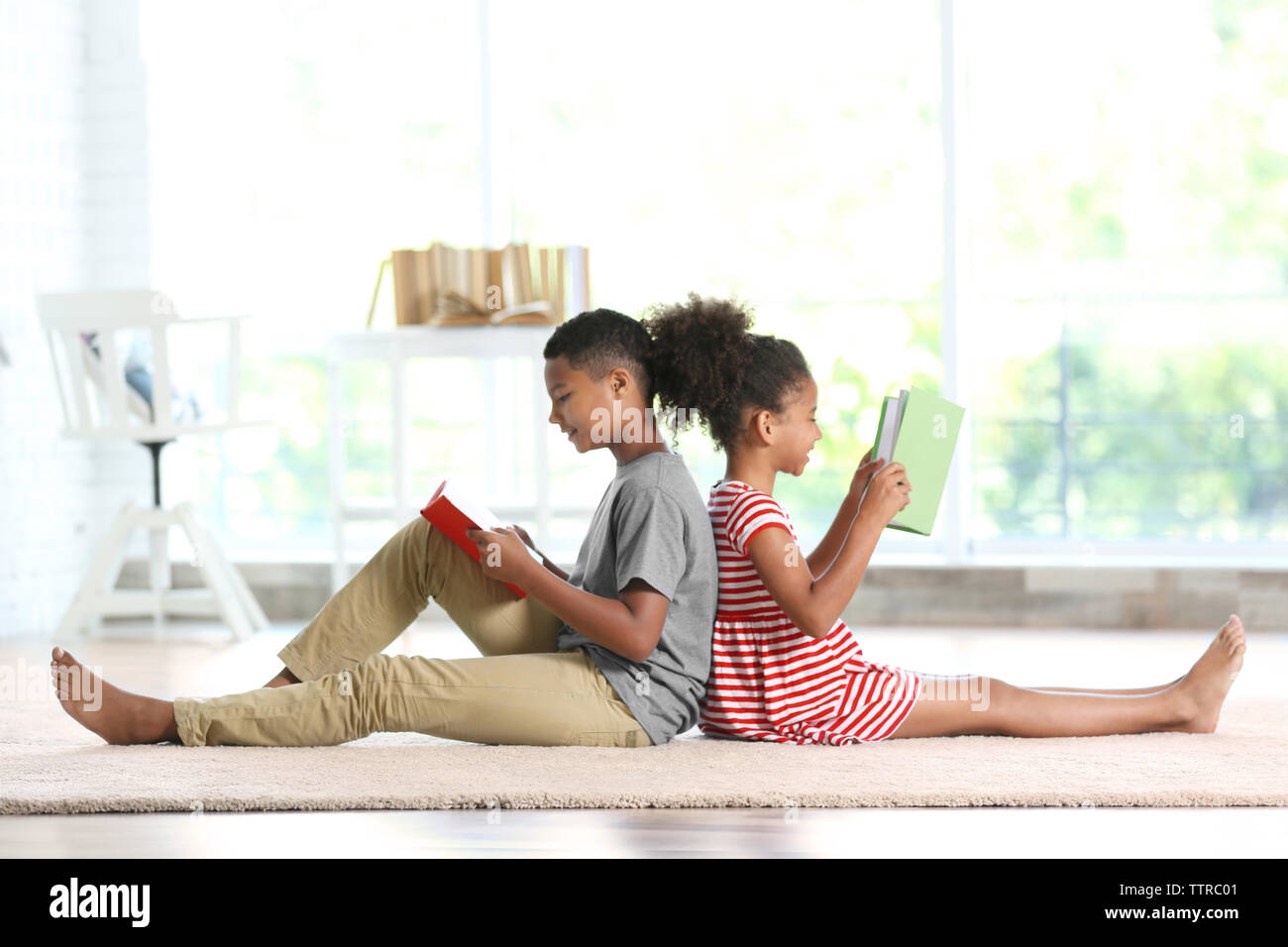 Cute boy and girl reading books at home Stock Photo - Alamy
