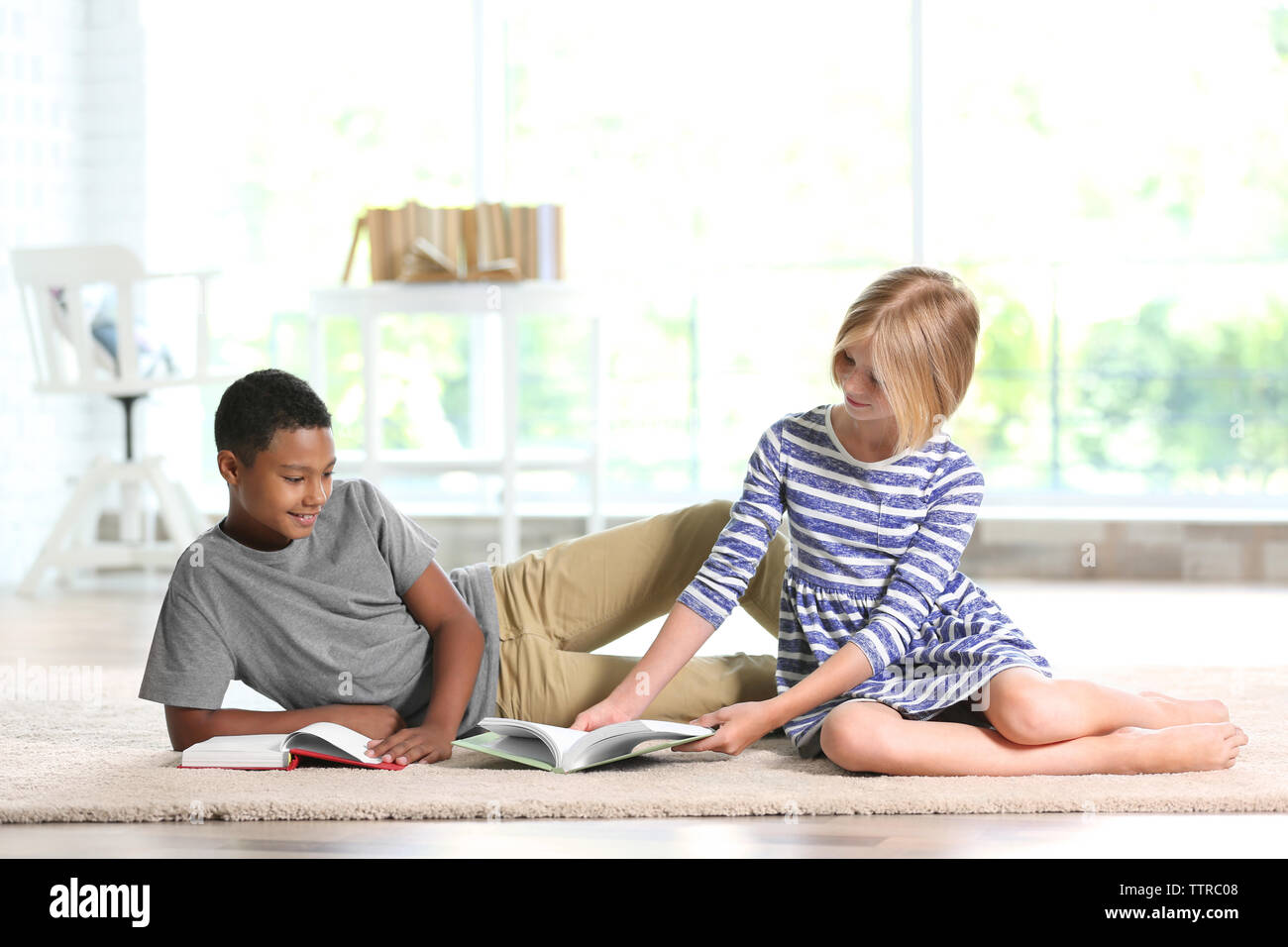 Cute boy and girl reading books at home Stock Photo - Alamy