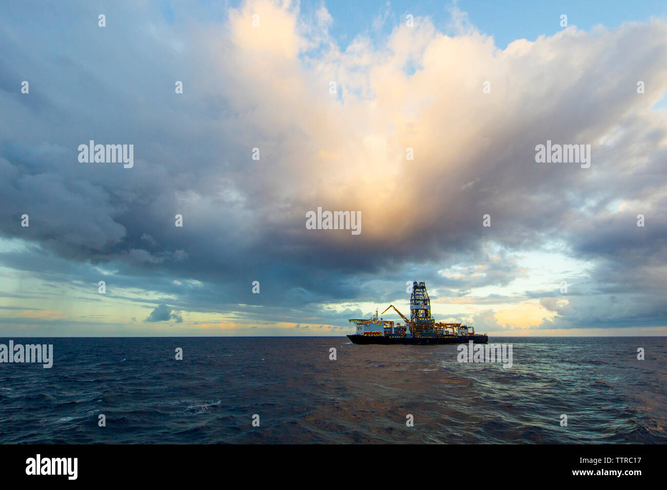 Drill ship in sea against cloudy sky Stock Photo