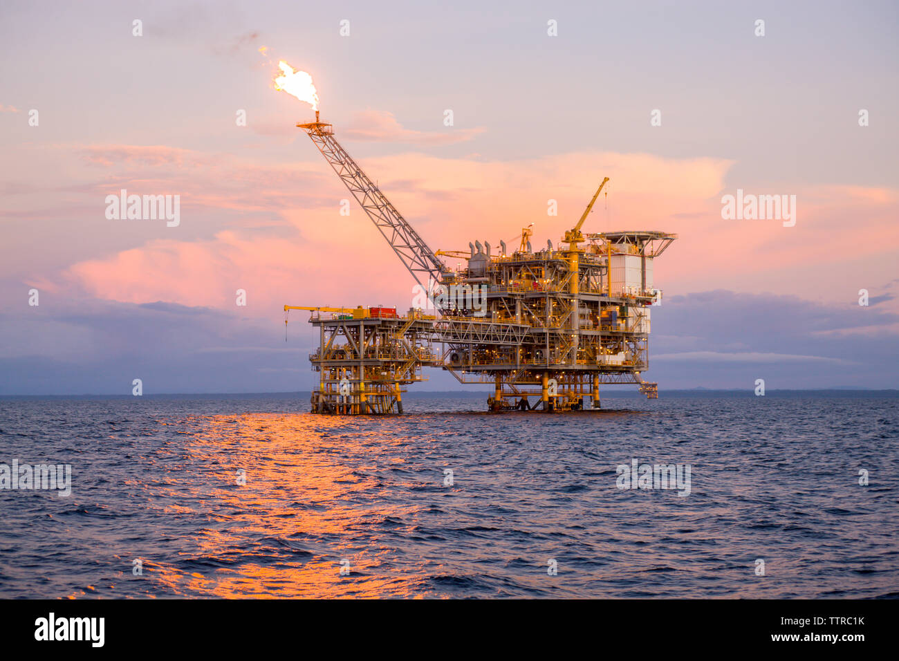 Offshore platform in sea against sky during sunset Stock Photo