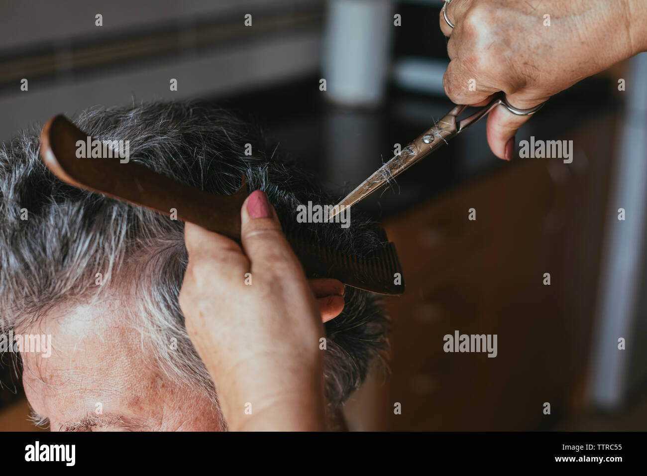 Cropped hands of female barber cutting male customer's hair Stock Photo