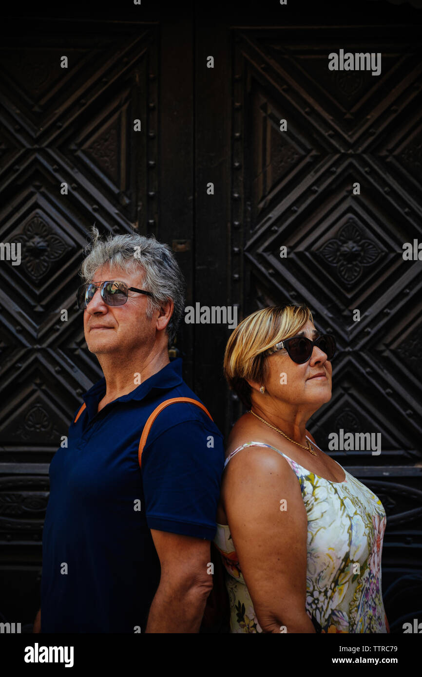 Senior couple wearing sunglasses while standing against closed doors Stock Photo