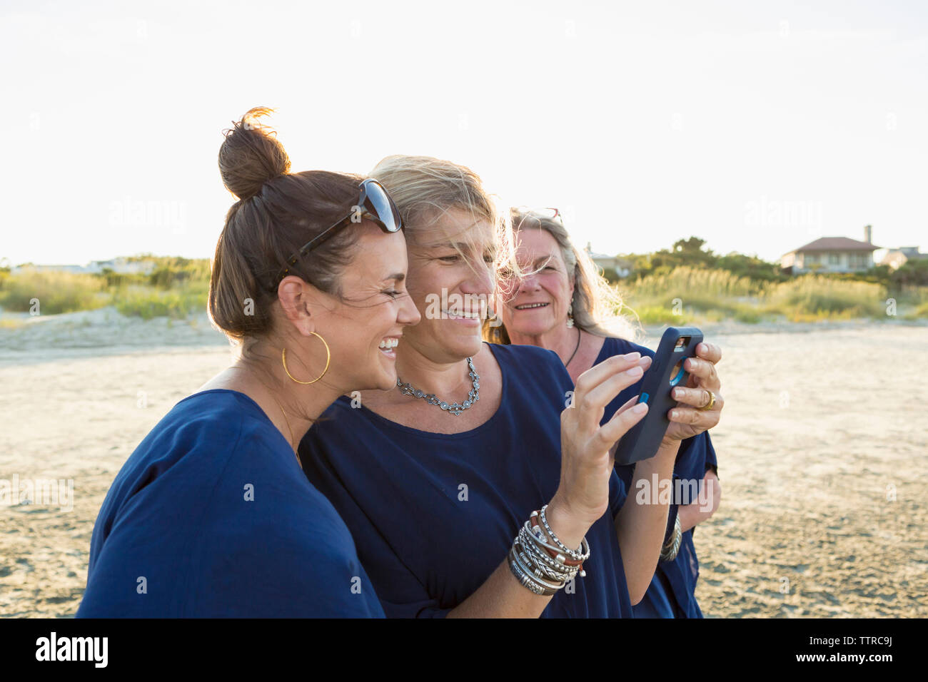 Women looking at smart phone while standing against clear sky Stock Photo
