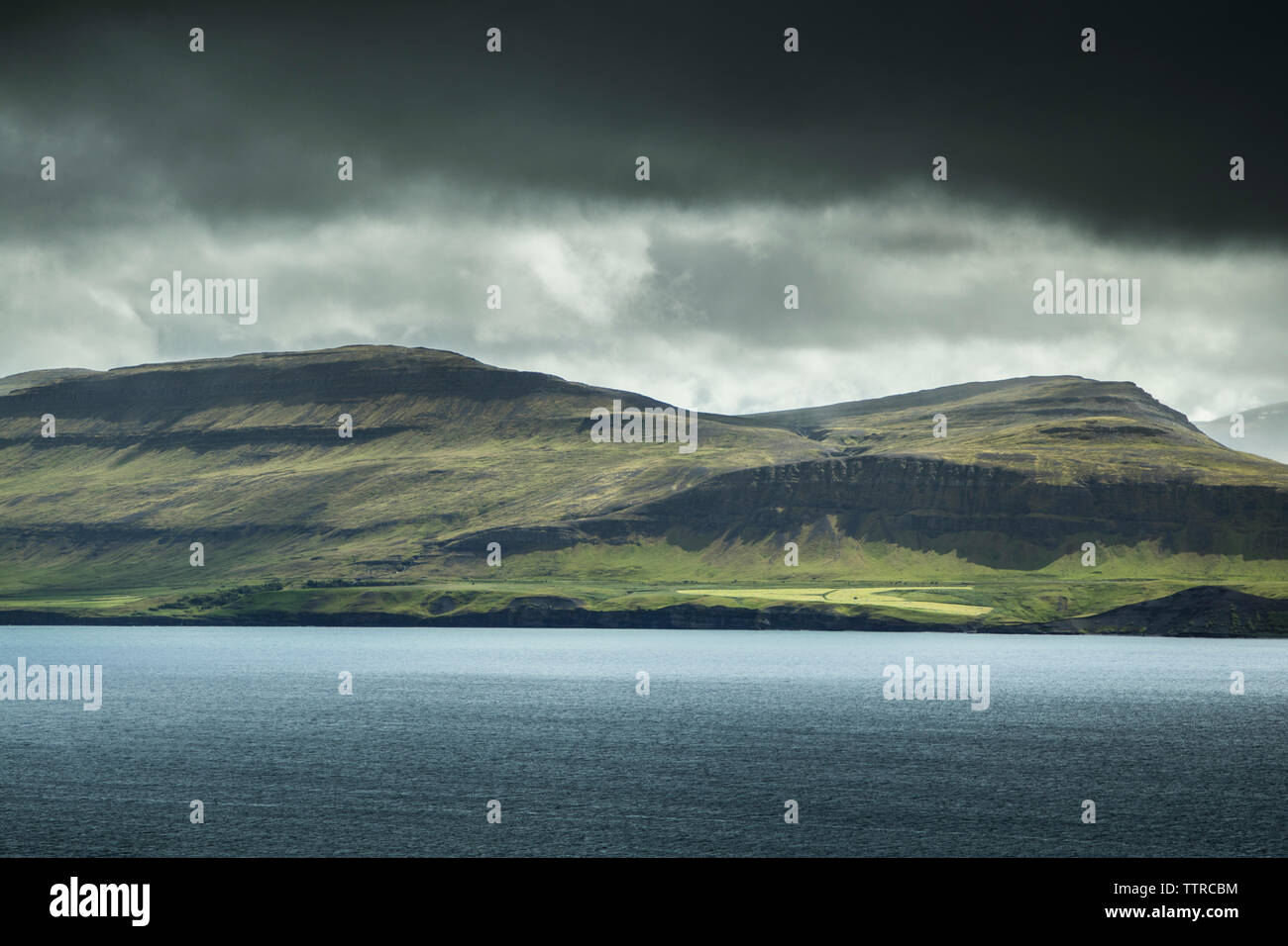 Scenic view of lake by mountains against stormy clouds Stock Photo - Alamy
