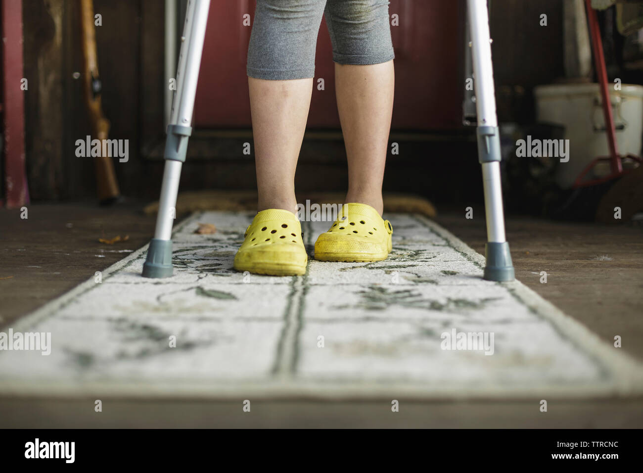 Low section of girl with crutches standing on rug at home Stock Photo