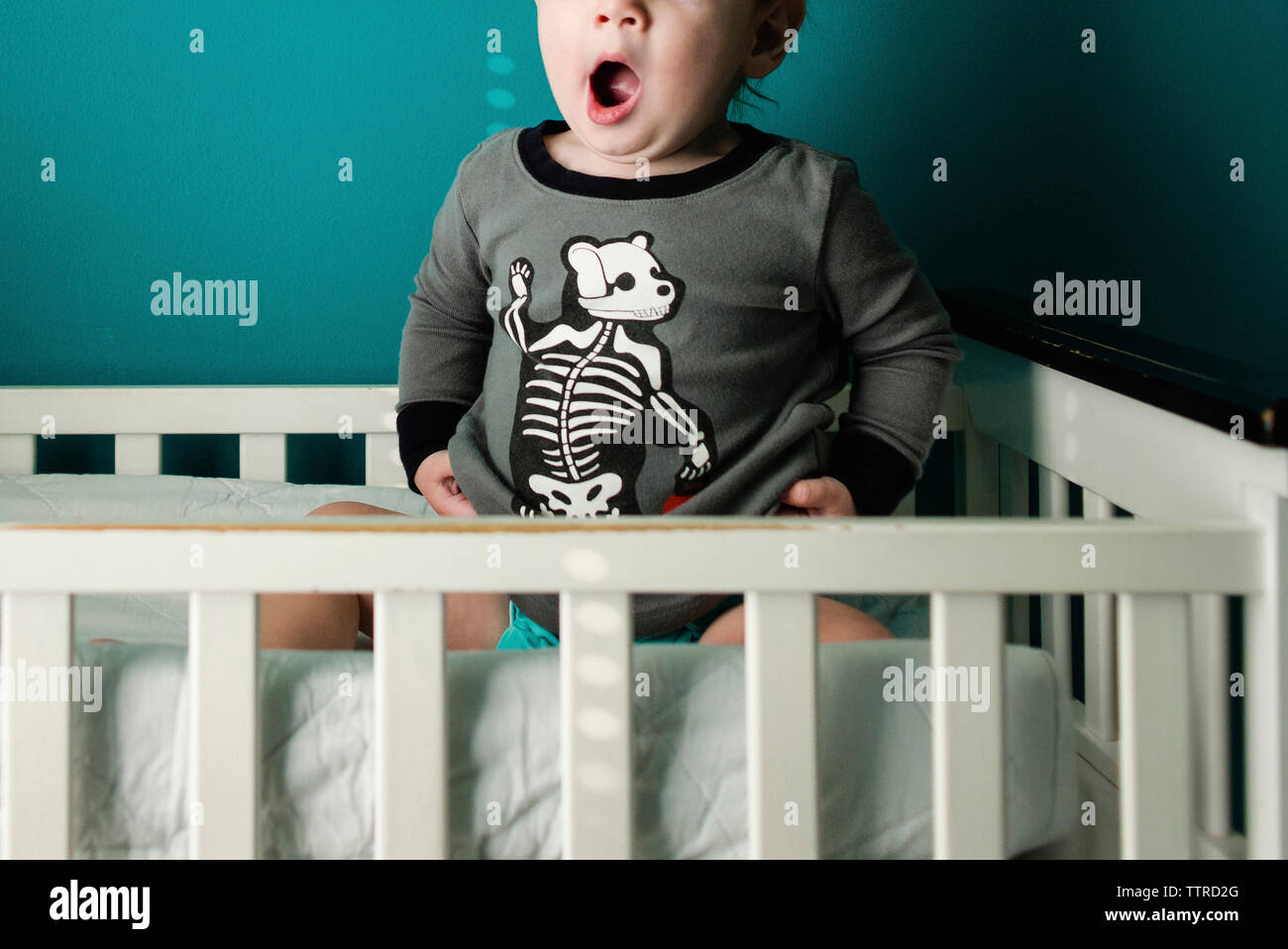 Midsection of boy yawning while sitting in bunkbed Stock Photo