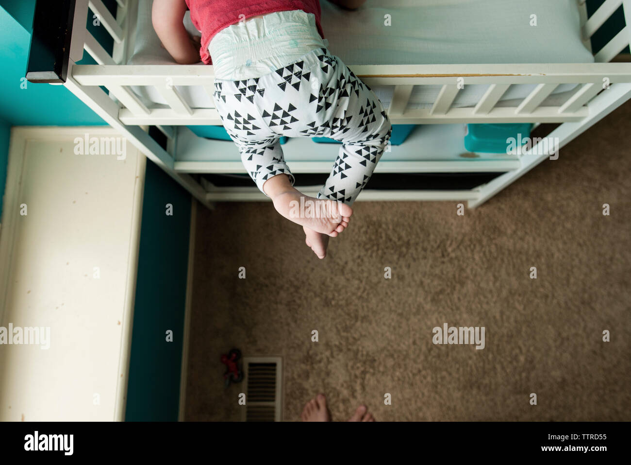 Low section of boy climbing bunkbed in bedroom Stock Photo