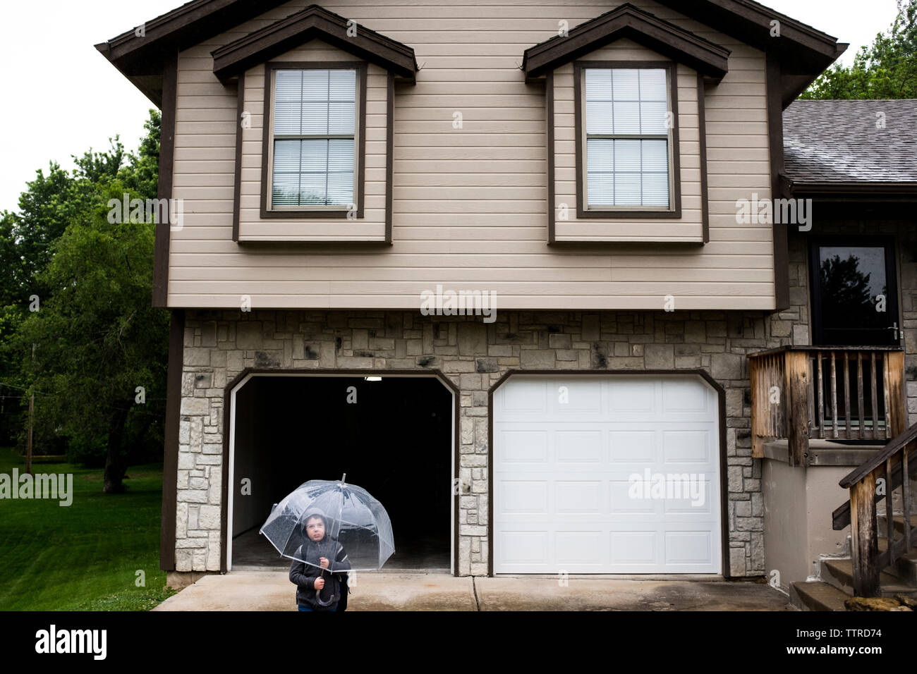 High angle view of boy holding umbrella while standing against house Stock Photo
