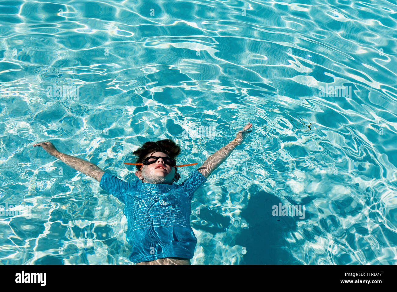 High angle view of boy with arms raised floating on water in swimming pool Stock Photo