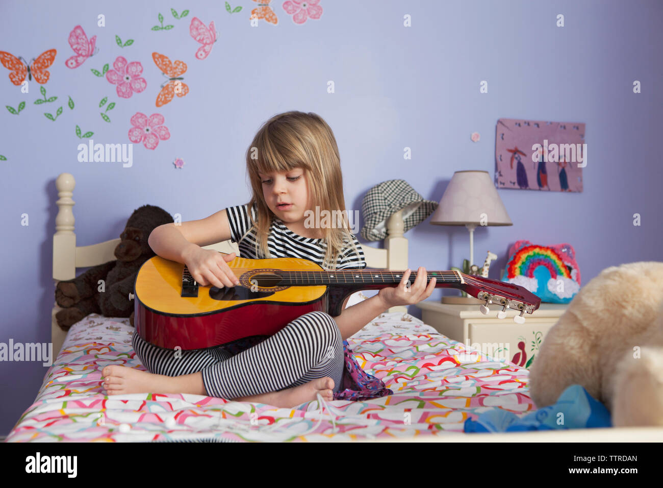 Girl playing guitar on bed at home Stock Photo Alamy
