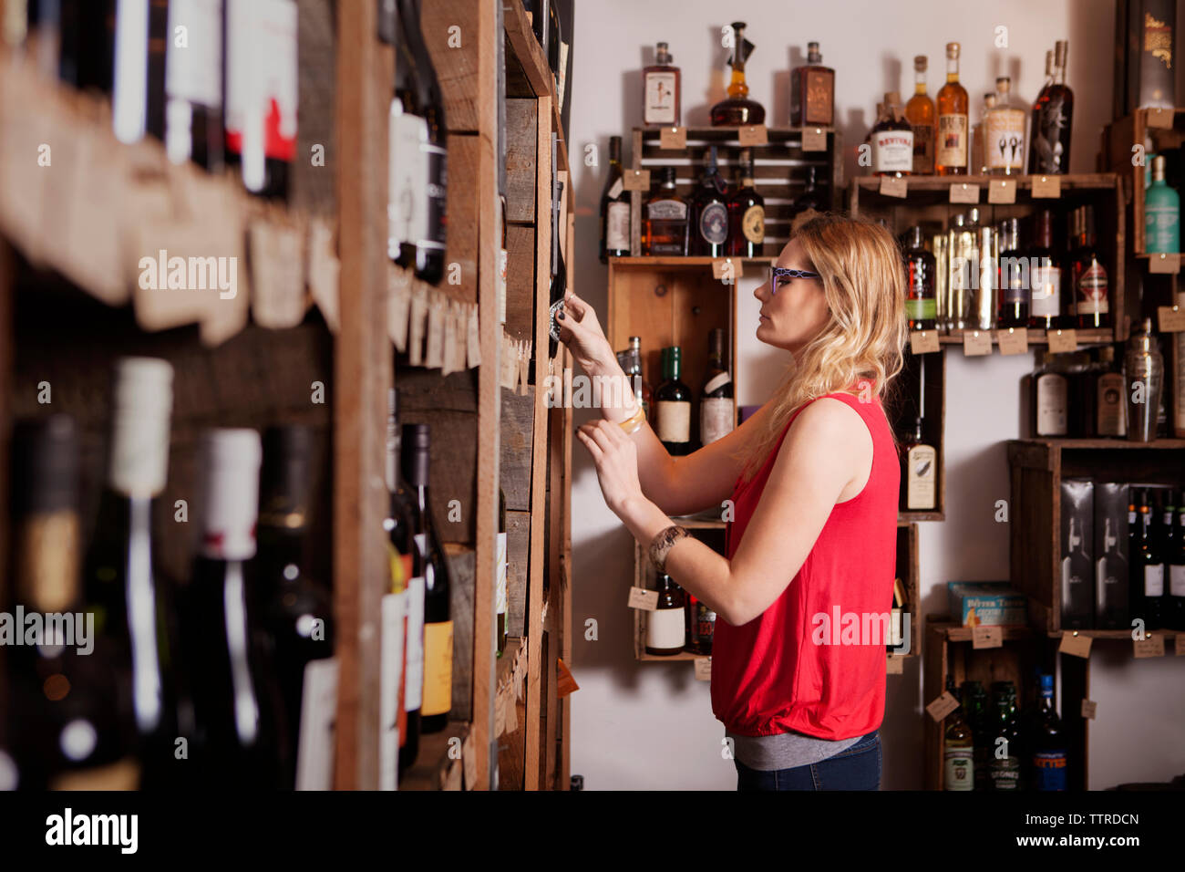 Side view of female business owner examining wine bottles at shop Stock Photo