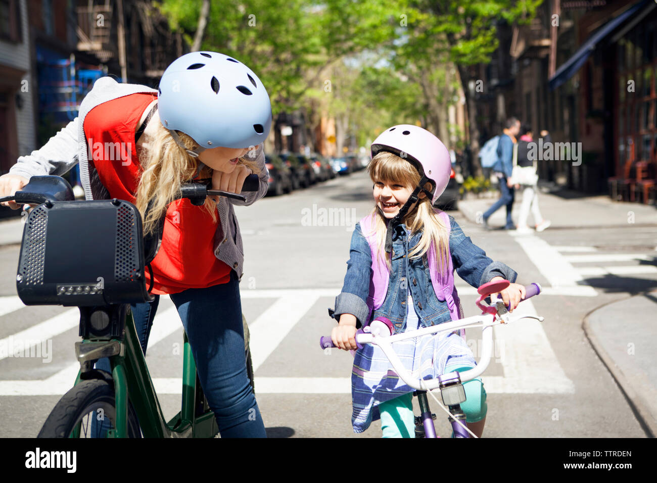 Happy woman talking to daughter while riding bicycles on street Stock Photo