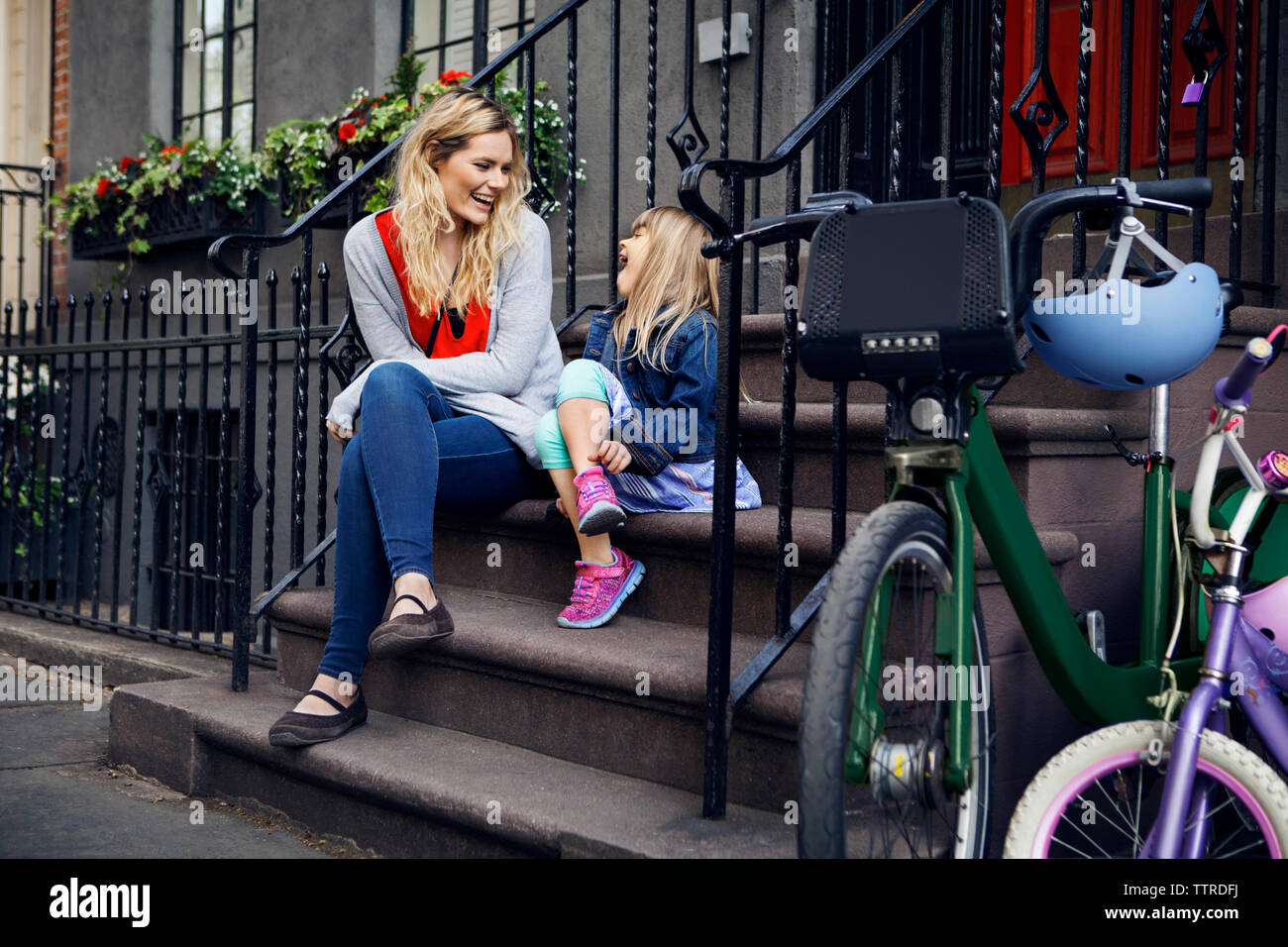 Happy mother and daughter talking while sitting on steps Stock Photo