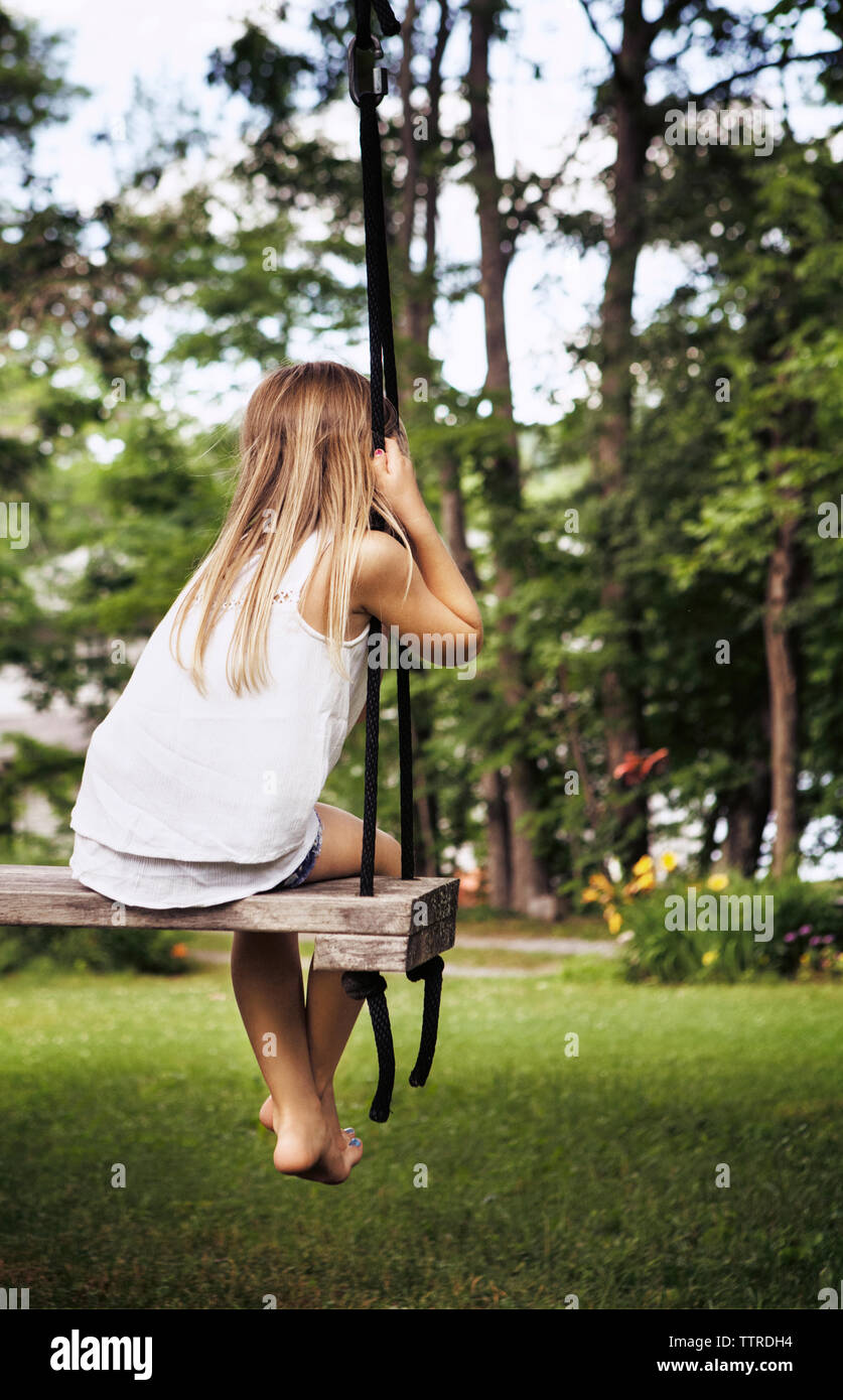Rear view of girl sitting on swing at park Stock Photo