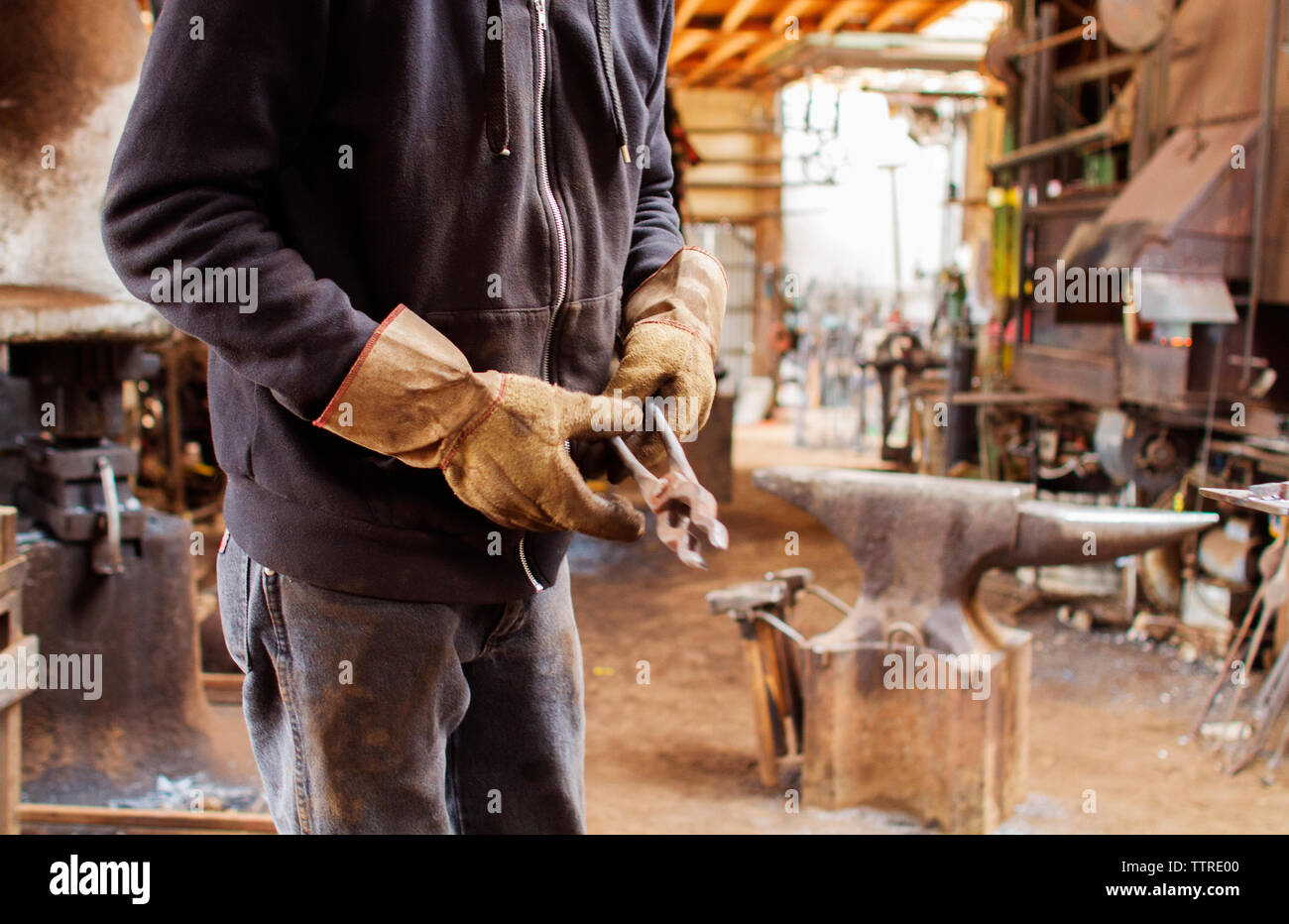 Midsection of craftsperson holding work tool at metal industry Stock Photo