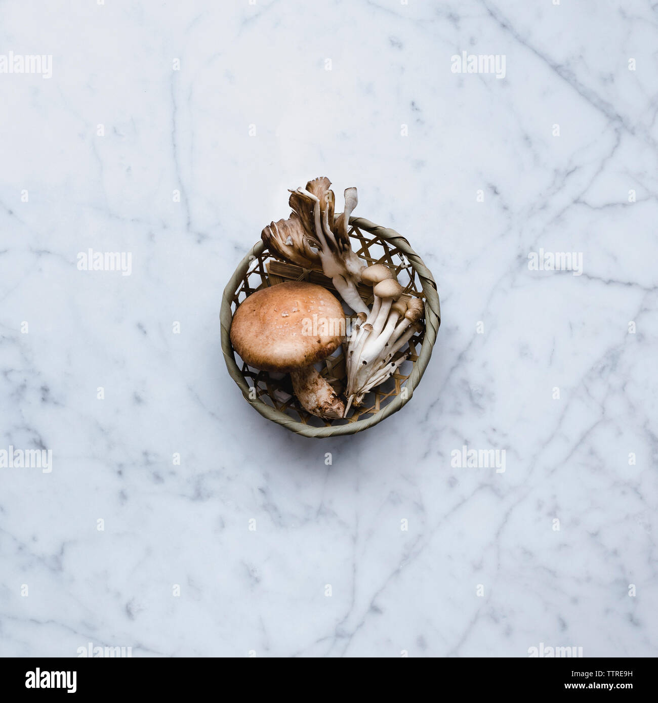 Overhead view of edible mushrooms in basket on table Stock Photo