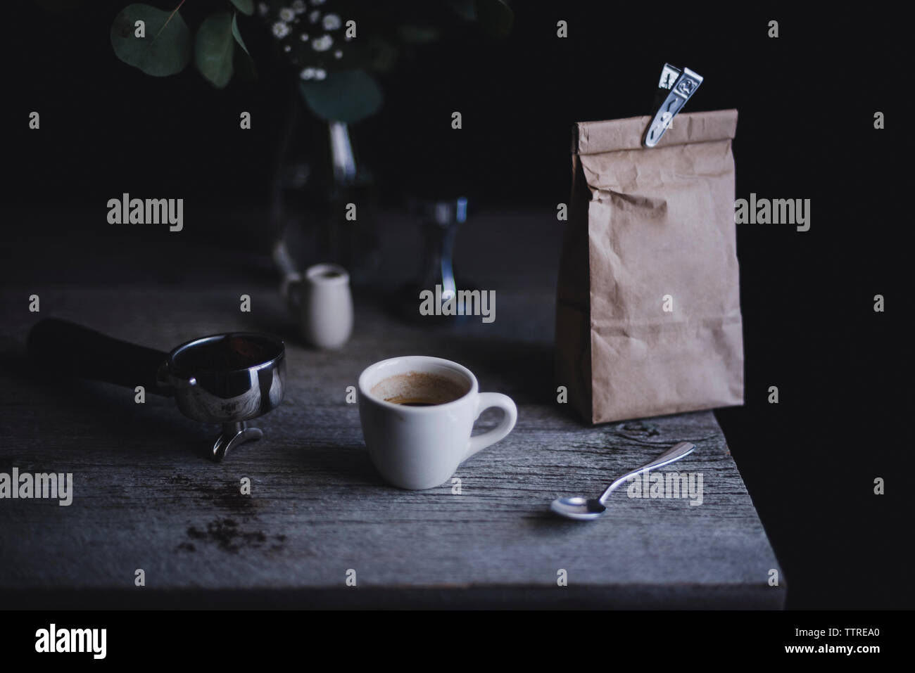Espresso cup with paper bag and portafilter on wooden table Stock Photo