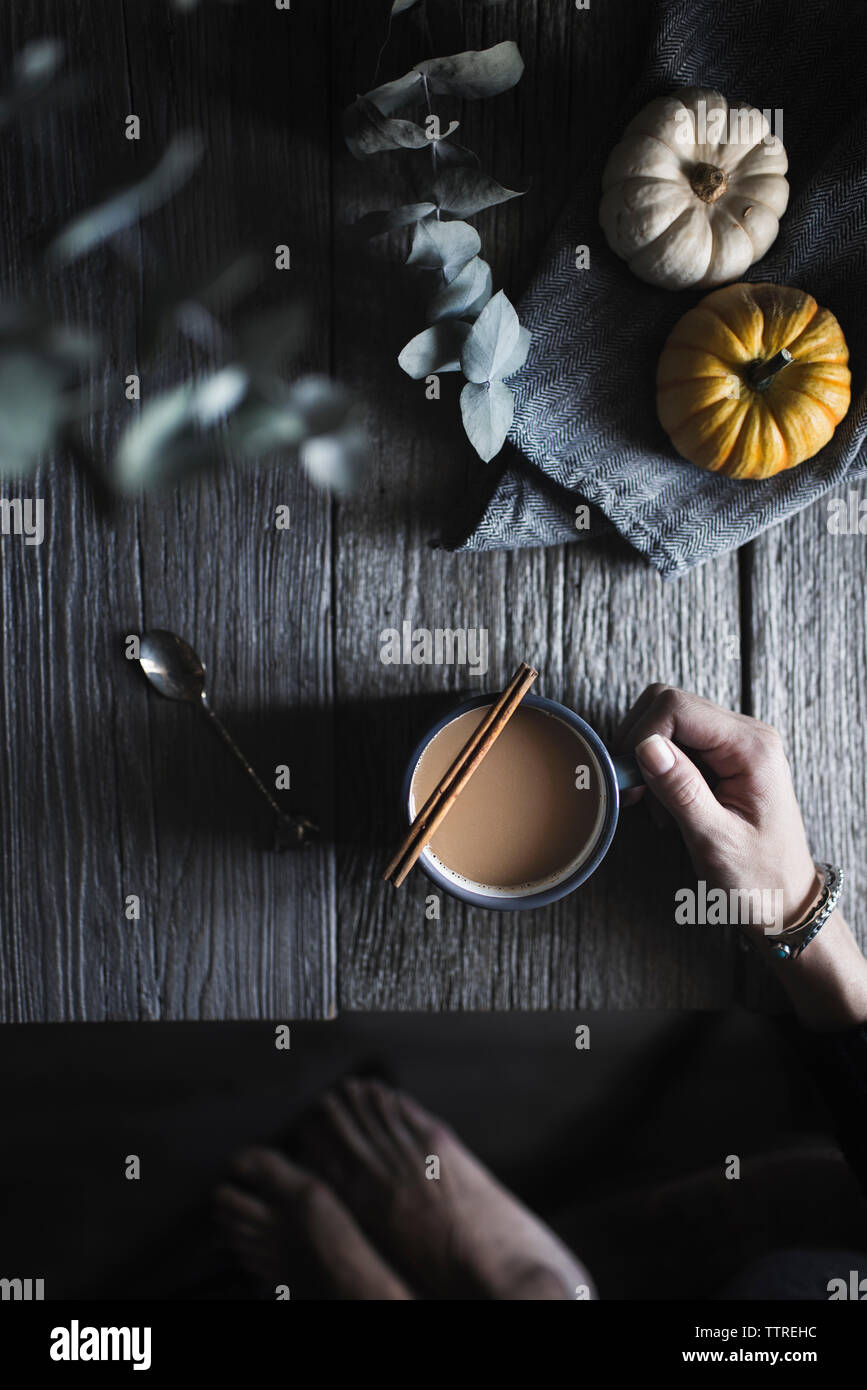 Cropped image of woman with coffee by pumpkins at table Stock Photo