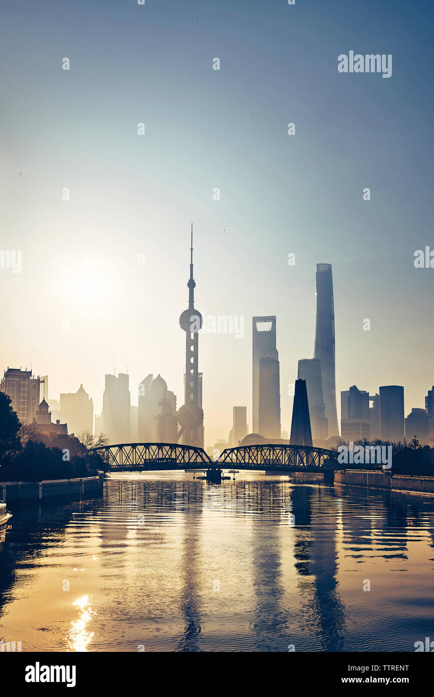 Silhouette bridge over Huangpu River against modern skyscrapers during sunset Stock Photo