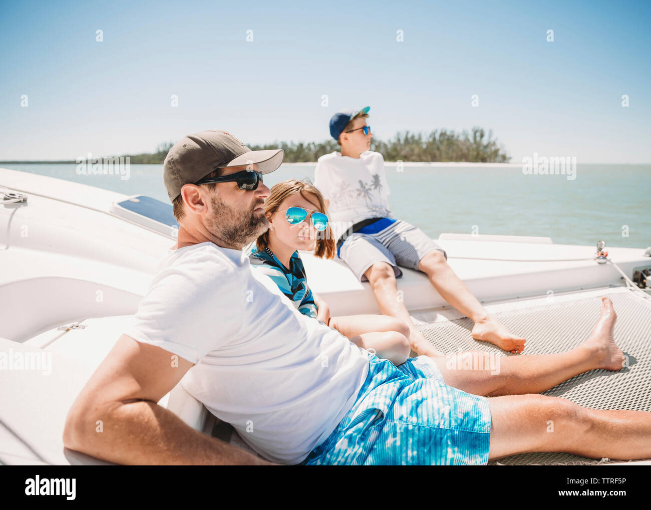 Family relaxing in boat on sea against clear sky during sunny day Stock Photo