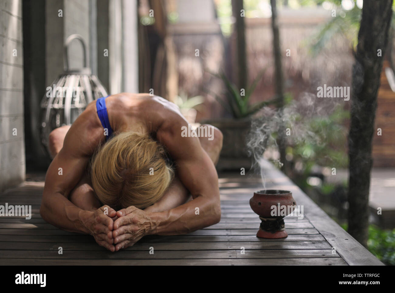 Muscular woman practicing yoga on porch Stock Photo