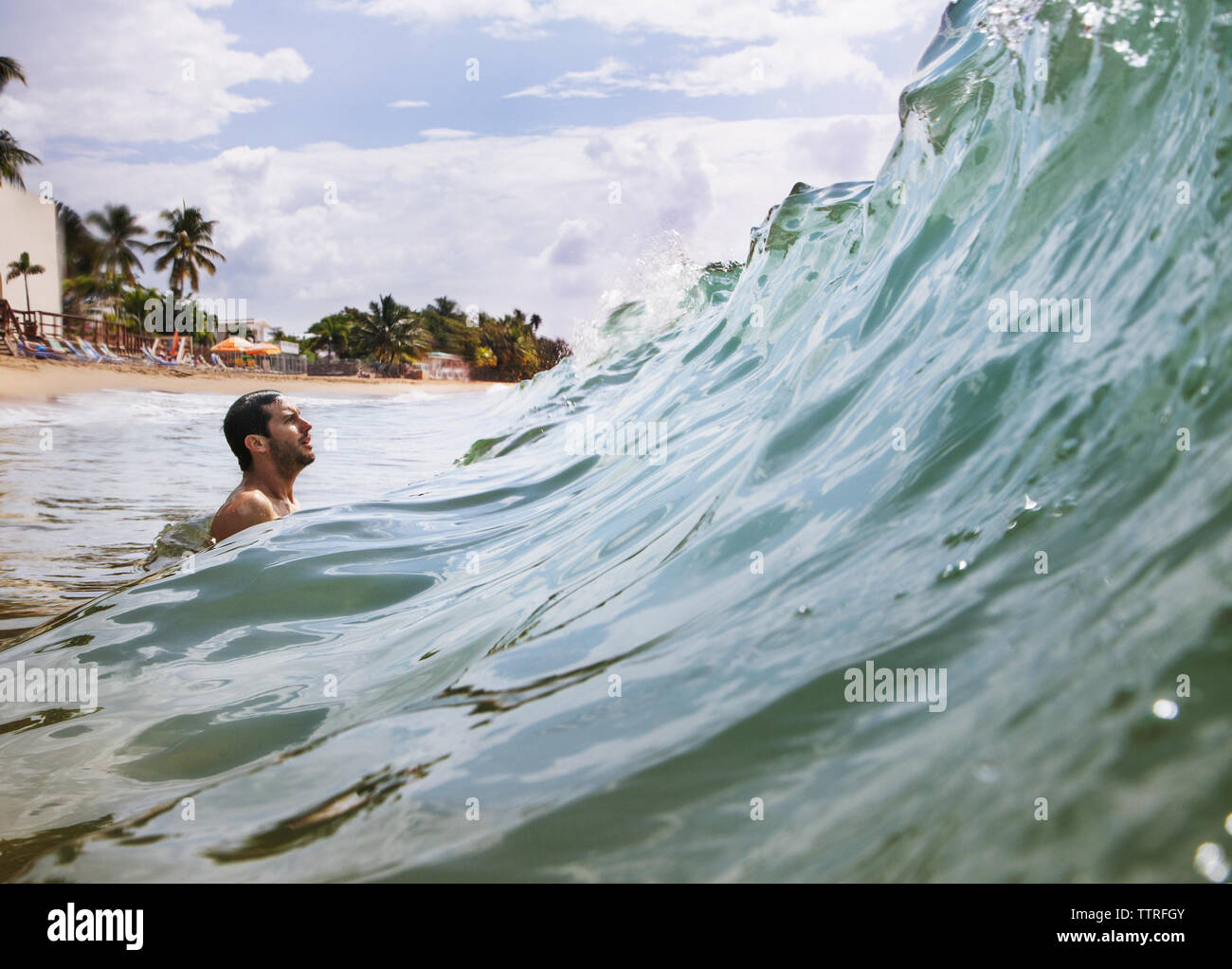 Side view of man enjoying sea wave while surfing against sky Stock Photo