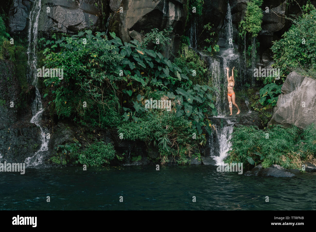 Woman in bikini enjoying waterfall at forest Stock Photo