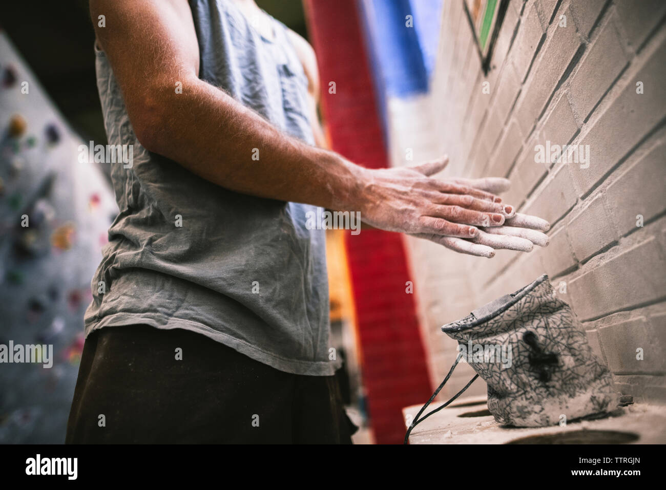 Midsection of sportsperson chalking hands while standing at gym Stock Photo