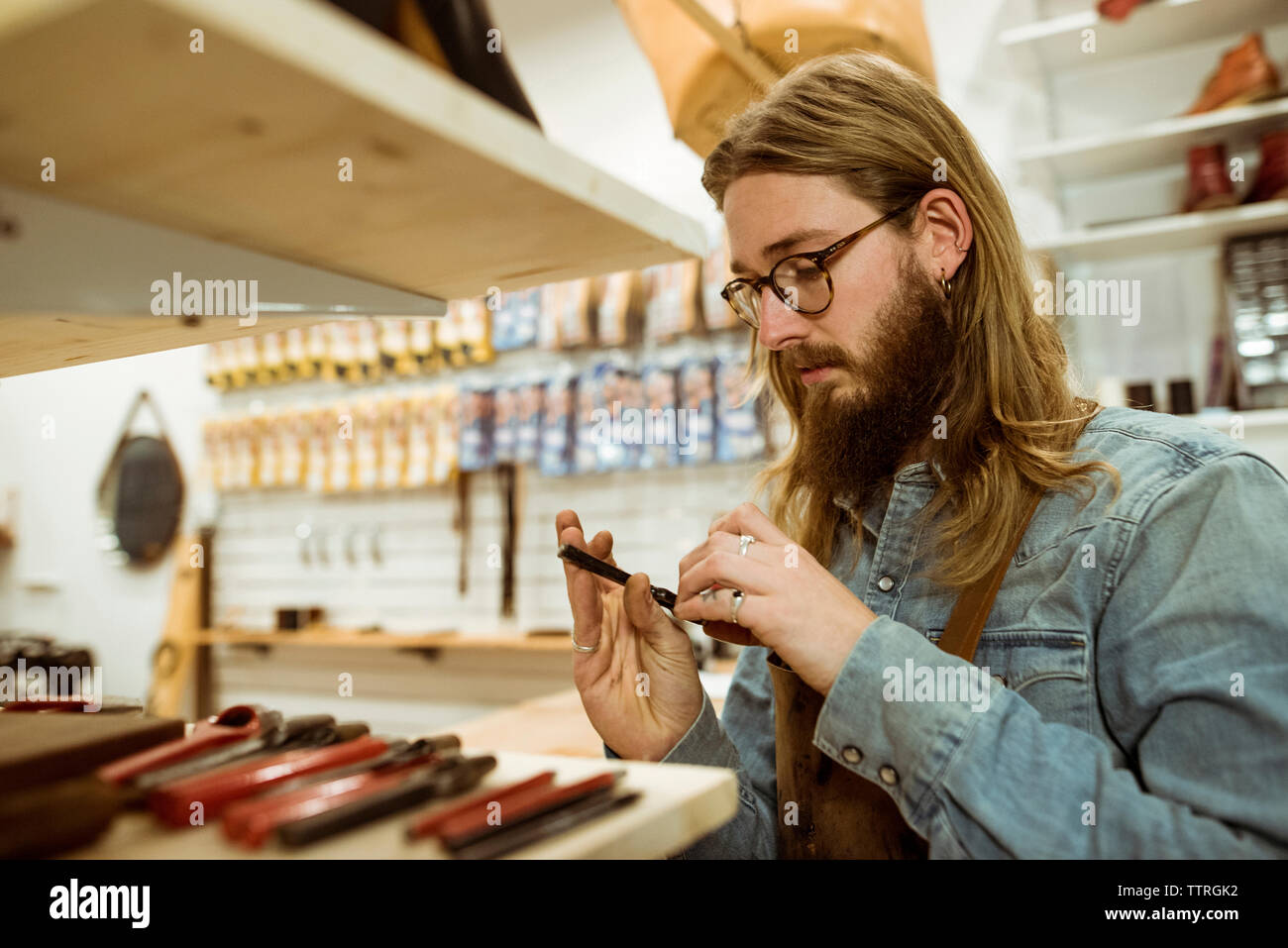 Shoemaker looking at tool in workshop Stock Photo