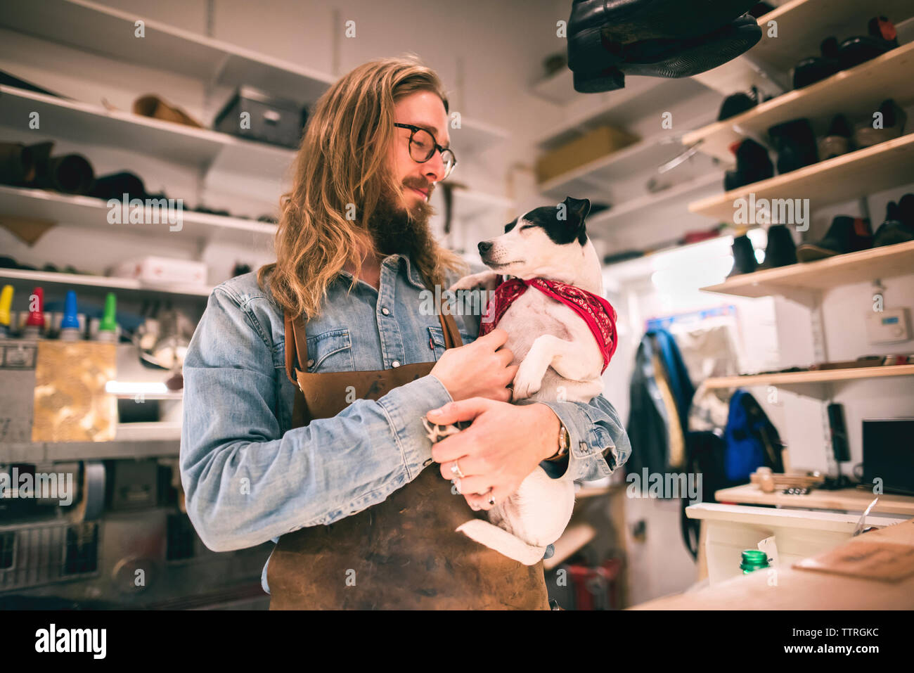 Shoemaker carrying dog while standing in workshop Stock Photo