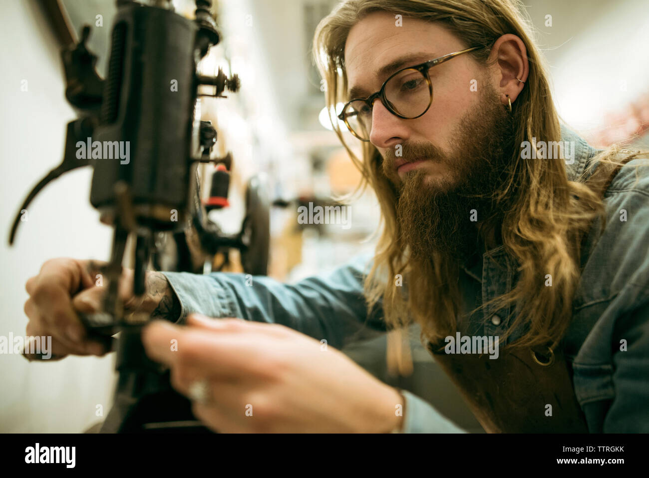 Serious shoemaker adjusting sewing machine at workshop Stock Photo