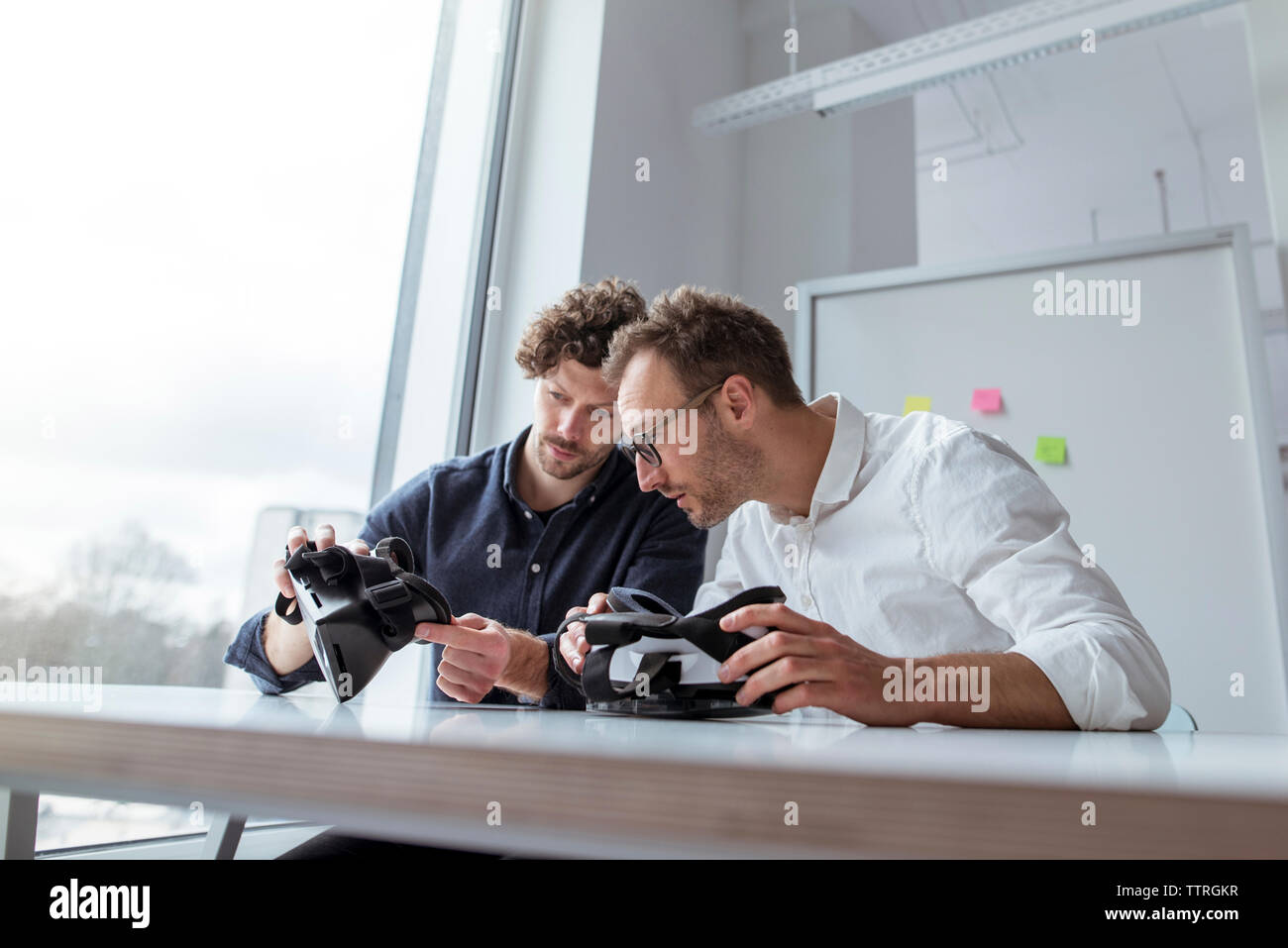 Engineers examining virtual reality simulators at table in office Stock Photo
