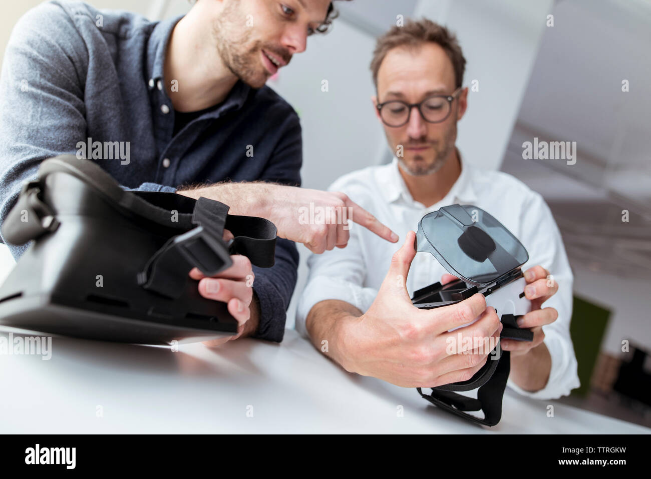 Engineers examining virtual reality simulators in office Stock Photo