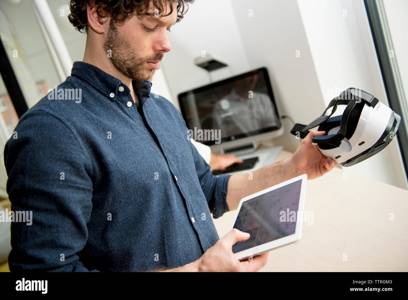 Engineer using tablet computer while examining virtual reality simulator in office Stock Photo