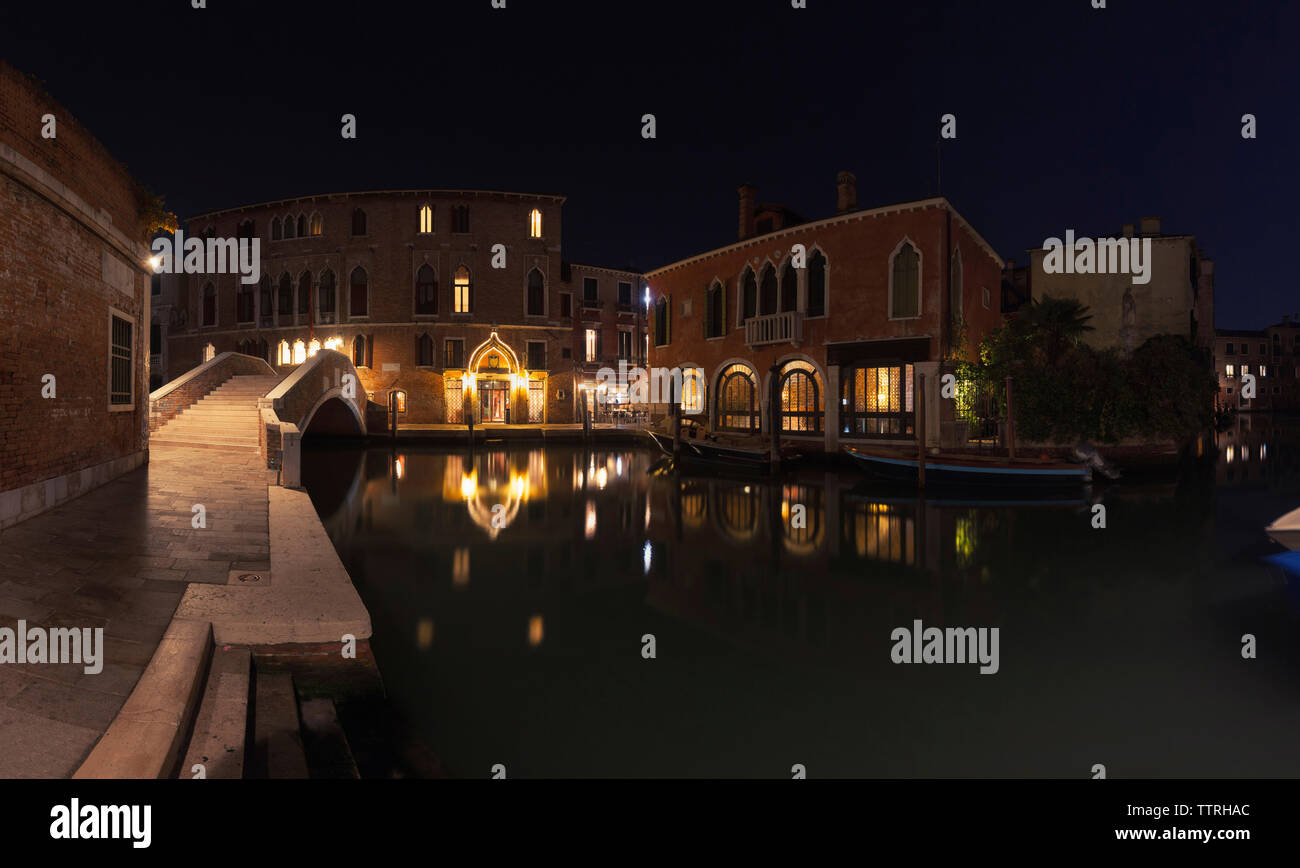 Illuminated residential buildings by canal in city at night Stock Photo
