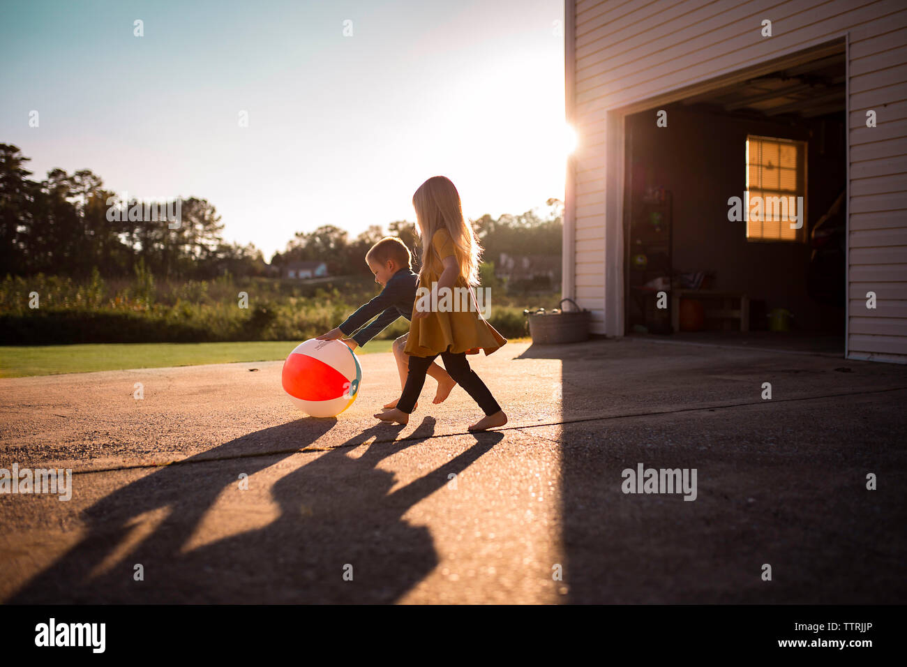 Playful siblings playing with ball at driveway Stock Photo