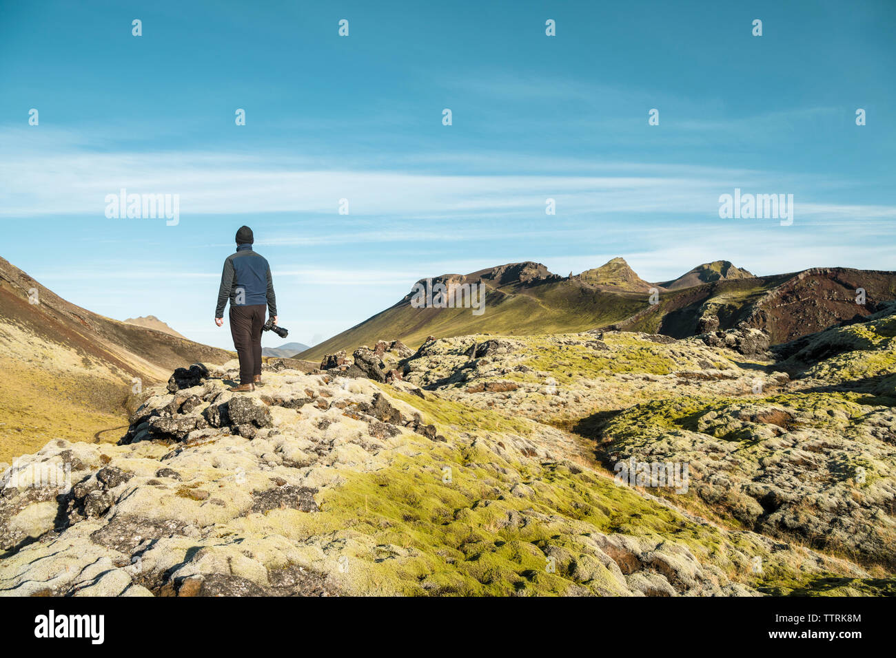 Full length of hiker with camera looking at view against sky Stock Photo